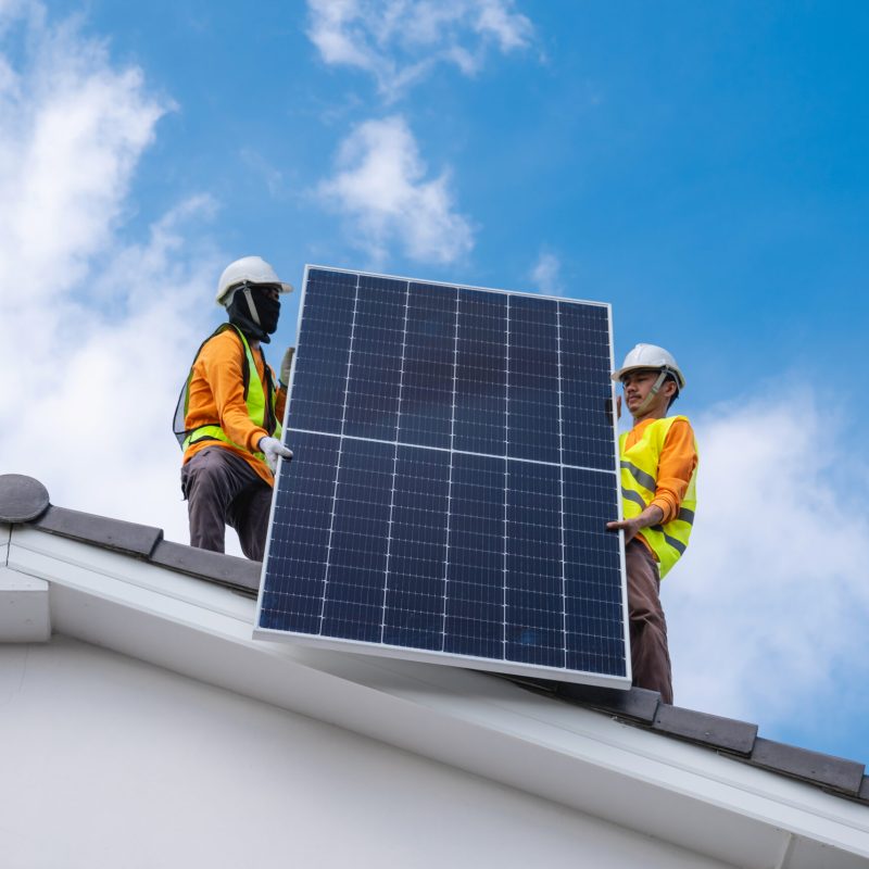 Service engineer installing solar cell on the roof of house. Technicians working about solar panel system outdoors. Clean and Renewable energy concept.
